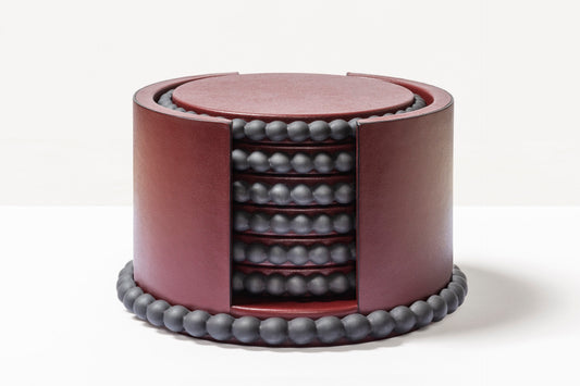 Giobagnara | Perla Round Coaster: Leather-covered round coaster with sculptural edge, available individually or with holder and set of six | Serveware + Hospitality / Coasters | 2Jour Concierge, your luxury lifestyle shop | luxury table details, premium coasters for expensive interiors, coffee tables, dining settings, and curated entertaining spaces