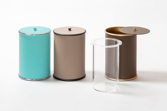 Giobagnara Ravello bin with lid | Part of the minimal Ravello bathroom collection | Cylindrical metal structure partially covered in velvety Italian leather | Features smooth rounded edges and a removable inner plexiglass container | Finished with polished chrome, brushed bronze, or brushed brass | Non-slip waterproof rubber base for practical elegance | Bathroom accessories | 2Jour Concierge, your luxury lifestyle shop