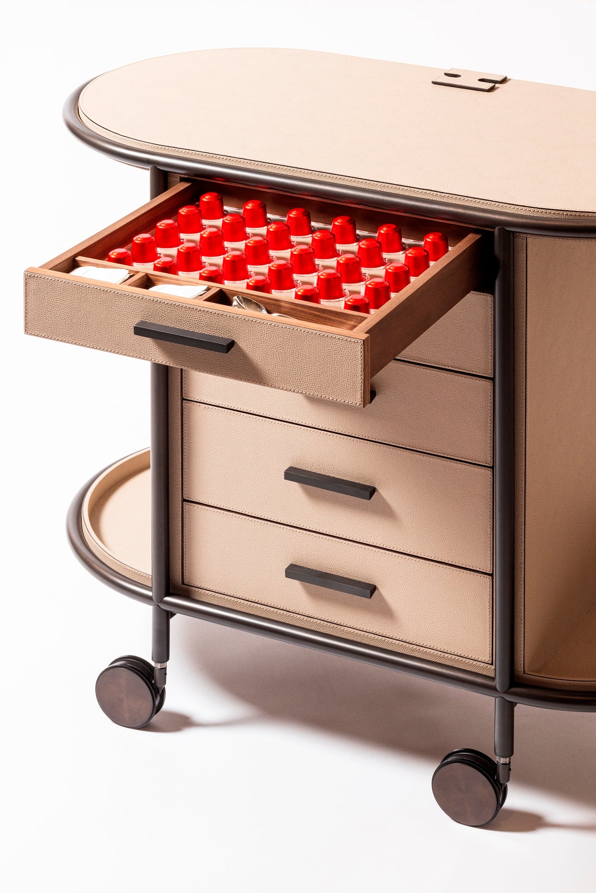 Giobagnara Arcade Coffee and Tea Cart Oval | Leather-covered four-wheel wooden structure with a metal frame and wheels available in three finishes | Features five drawers with sleek metal handles for organized storage of coffee capsules and tea bags | Includes a luxurious set of porcelain coffee and tea cups with matching plates, leather service trays, and coasters | Designed for mobility, combining functionality and sophistication | Furniture and Serveware | 2Jour Concierge, your luxury lifestyle shop