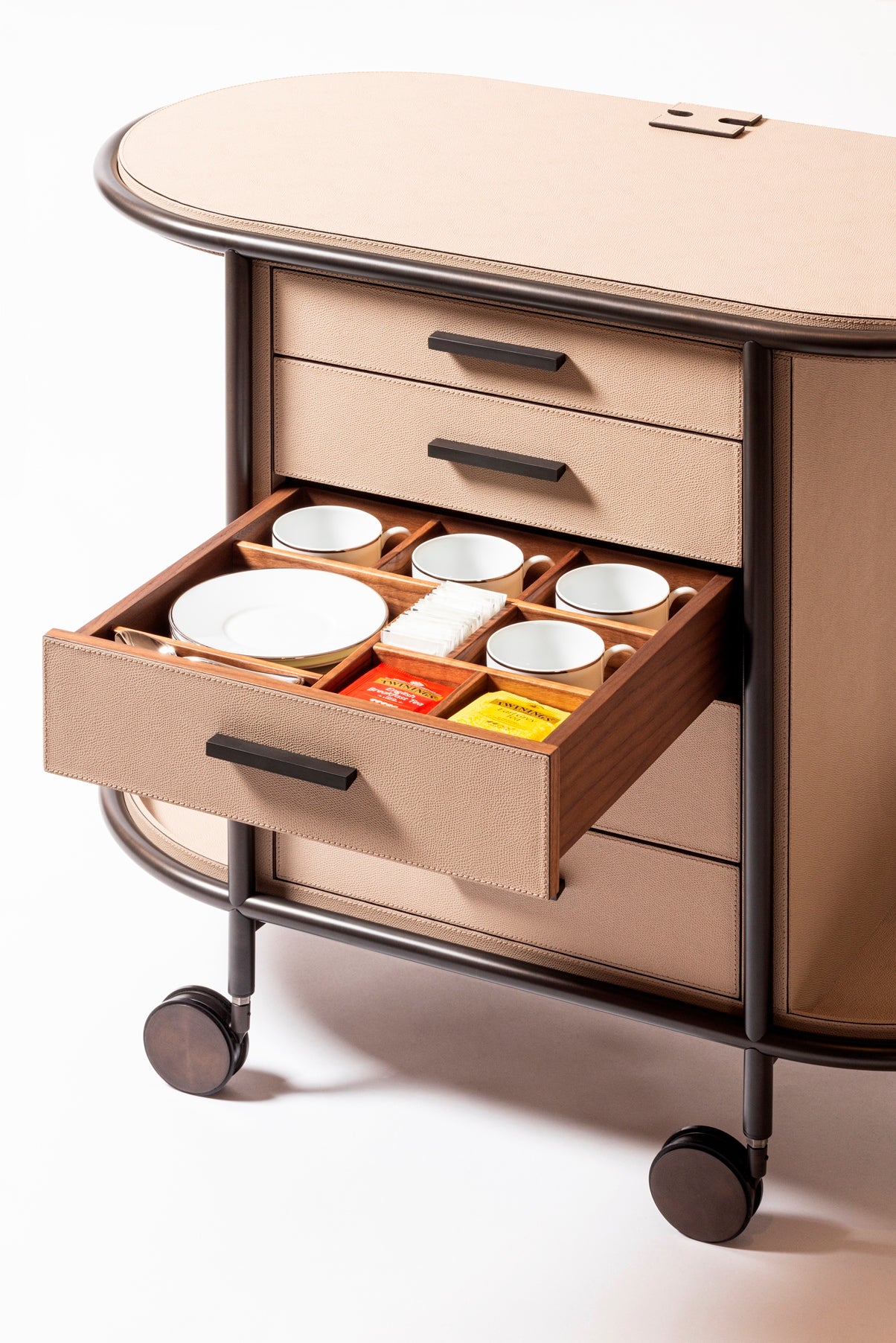 Giobagnara Arcade Coffee and Tea Cart Oval | Leather-covered four-wheel wooden structure with a metal frame and wheels available in three finishes | Features five drawers with sleek metal handles for organized storage of coffee capsules and tea bags | Includes a luxurious set of porcelain coffee and tea cups with matching plates, leather service trays, and coasters | Designed for mobility, combining functionality and sophistication | Furniture and Serveware | 2Jour Concierge, your luxury lifestyle shop
