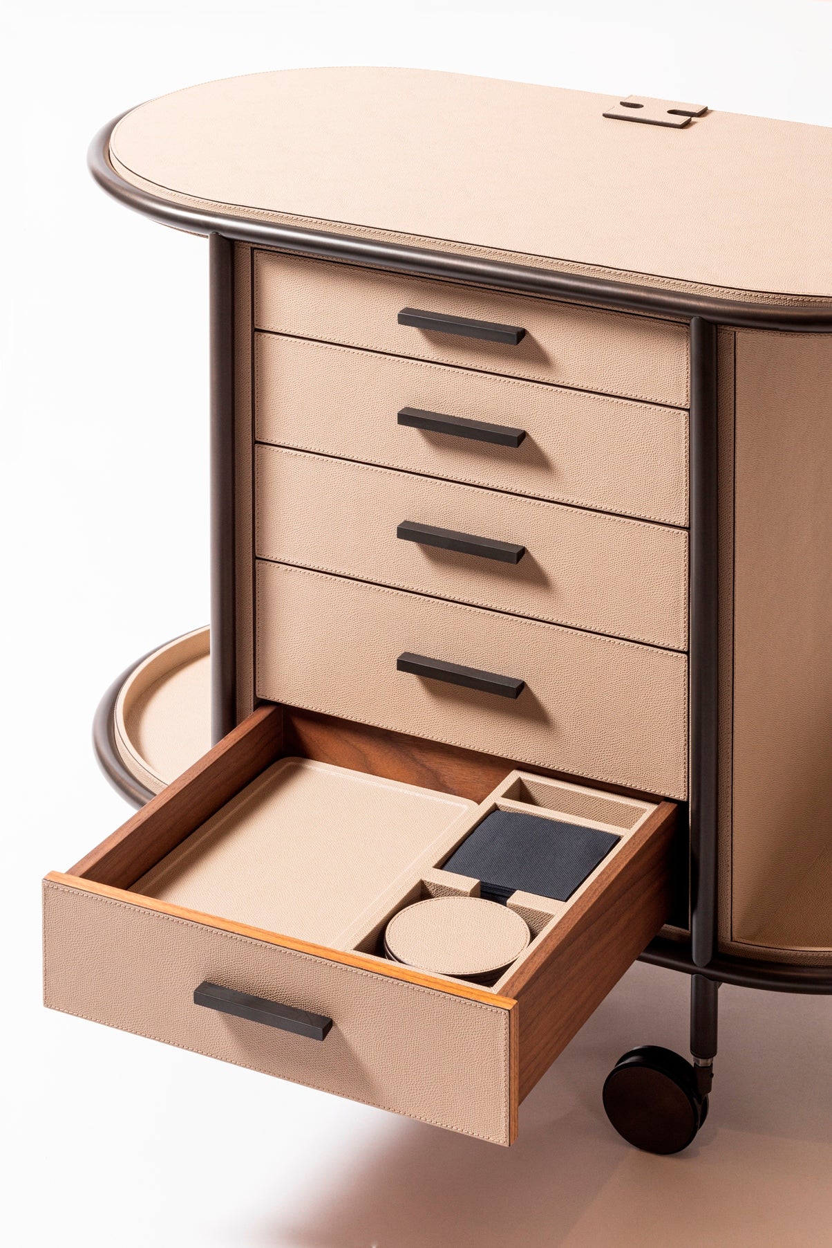 Giobagnara Arcade Coffee and Tea Cart Oval | Leather-covered four-wheel wooden structure with a metal frame and wheels available in three finishes | Features five drawers with sleek metal handles for organized storage of coffee capsules and tea bags | Includes a luxurious set of porcelain coffee and tea cups with matching plates, leather service trays, and coasters | Designed for mobility, combining functionality and sophistication | Furniture and Serveware | 2Jour Concierge, your luxury lifestyle shop