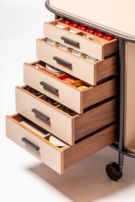 Giobagnara Arcade Coffee and Tea Cart Oval | Leather-covered four-wheel wooden structure with a metal frame and wheels available in three finishes | Features five drawers with sleek metal handles for organized storage of coffee capsules and tea bags | Includes a luxurious set of porcelain coffee and tea cups with matching plates, leather service trays, and coasters | Designed for mobility, combining functionality and sophistication | Furniture and Serveware | 2Jour Concierge, your luxury lifestyle shop