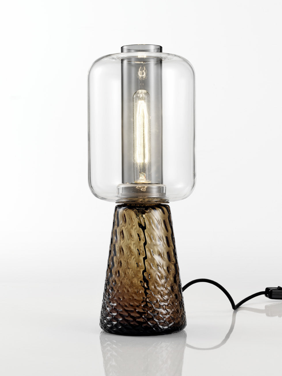 NasonMoretti Ensemble table lamp | Handcrafted in Murano glass with balloon texture and ancient crystal lightness | A poetic design by Elena Salmistraro, celebrating the beauty of everyday objects through interlocks and overlaps | Earth-toned glass base in grey or brown paired with a clear glass diffuser evokes a natural elegance | A sculptural lighting piece that blends function with artistry | Home lighting & decor | 2Jour Concierge, your luxury lifestyle shop