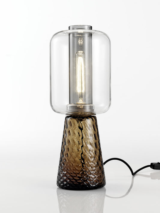 NasonMoretti Ensemble table lamp | Handcrafted in Murano glass with balloon texture and ancient crystal lightness | A poetic design by Elena Salmistraro, celebrating the beauty of everyday objects through interlocks and overlaps | Earth-toned glass base in grey or brown paired with a clear glass diffuser evokes a natural elegance | A sculptural lighting piece that blends function with artistry | Home lighting & decor | 2Jour Concierge, your luxury lifestyle shop