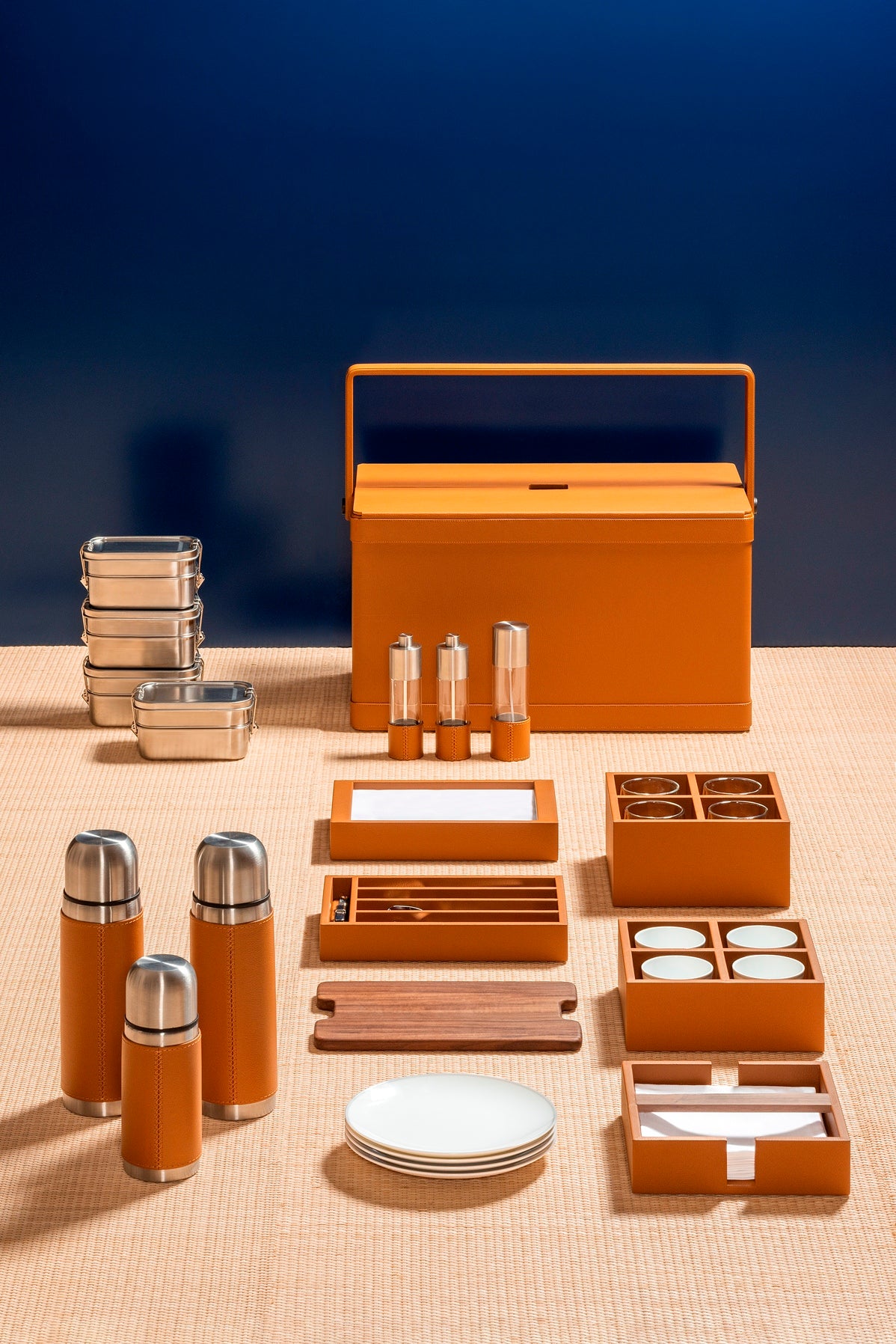 Giobagnara x Poltrona Frau picnic trunk | Leather-covered structure with tilting solid handle, designed for portability and elegance | Fully equipped with a complete picnic set including borosilicate glasses, thermoses, food containers, porcelain plates and cups, cutlery, and more | Walnut chopping board, fine cotton accessories, and leather-covered grinders included | Entirely made in Pelle Frau® | Home accessories & travel essentials | 2Jour Concierge, your luxury lifestyle shop