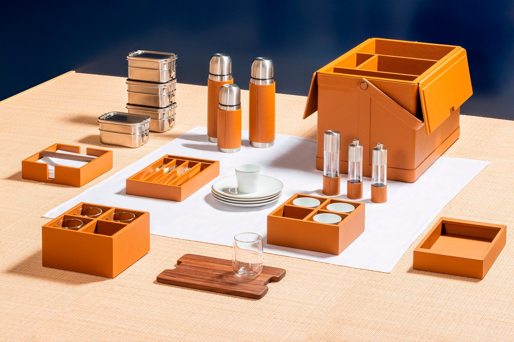 Giobagnara x Poltrona Frau picnic trunk | Leather-covered structure with tilting solid handle, designed for portability and elegance | Fully equipped with a complete picnic set including borosilicate glasses, thermoses, food containers, porcelain plates and cups, cutlery, and more | Walnut chopping board, fine cotton accessories, and leather-covered grinders included | Entirely made in Pelle Frau® | Home accessories & travel essentials | 2Jour Concierge, your luxury lifestyle shop