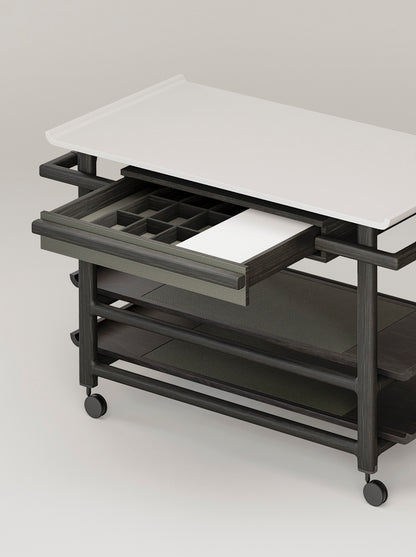 Giobagnara x Glenn Sestig Lloyd Tabi serving trolley | Elegant serving cart with a Corian® top and fine leather-lined drawer | Wood structure available in dark walnut, wenge, or natural finishes | Includes Corian® chopping board and removable wooden dividers for customizable storage | Features burnished brushed bronze wheels for smooth mobility | A refined and functional piece for serving and organizing essentials | Home furniture & serving accessories | 2Jour Concierge, your luxury lifestyle shop