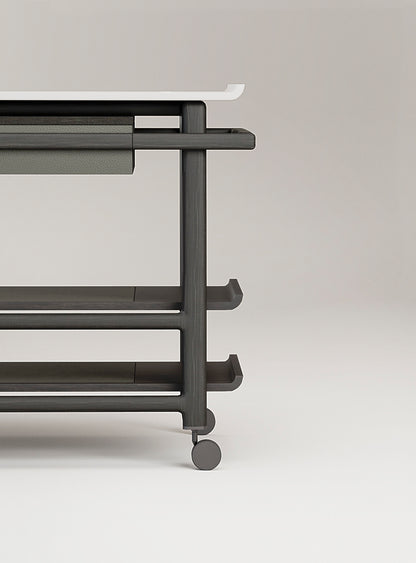 Giobagnara x Glenn Sestig Lloyd Tabi serving trolley | Elegant serving cart with a Corian® top and fine leather-lined drawer | Wood structure available in dark walnut, wenge, or natural finishes | Includes Corian® chopping board and removable wooden dividers for customizable storage | Features burnished brushed bronze wheels for smooth mobility | A refined and functional piece for serving and organizing essentials | Home furniture & serving accessories | 2Jour Concierge, your luxury lifestyle shop