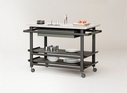 Giobagnara x Glenn Sestig Lloyd Tabi serving trolley | Elegant serving cart with a Corian® top and fine leather-lined drawer | Wood structure available in dark walnut, wenge, or natural finishes | Includes Corian® chopping board and removable wooden dividers for customizable storage | Features burnished brushed bronze wheels for smooth mobility | A refined and functional piece for serving and organizing essentials | Home furniture & serving accessories | 2Jour Concierge, your luxury lifestyle shop