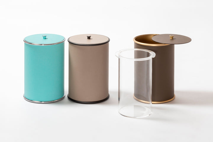 Giobagnara Ravello bin with lid | Part of the minimal Ravello bathroom collection | Cylindrical metal structure partially covered in velvety Italian leather | Features smooth rounded edges and a removable inner plexiglass container | Finished with polished chrome, brushed bronze, or brushed brass | Non-slip waterproof rubber base for practical elegance | Bathroom accessories | 2Jour Concierge, your luxury lifestyle shop