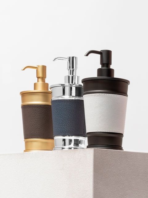 Giobagnara Manhattan soap dispenser | Part of the Manhattan bathroom collection | Features an inverted truncated cone metal structure with fine leather inserts | Decorative indentations create a modern architectural look | Non-slip waterproof rubber base | Available in chrome, bronze, or brass finishes | Bathroom accessories | 2Jour Concierge, your luxury lifestyle shop