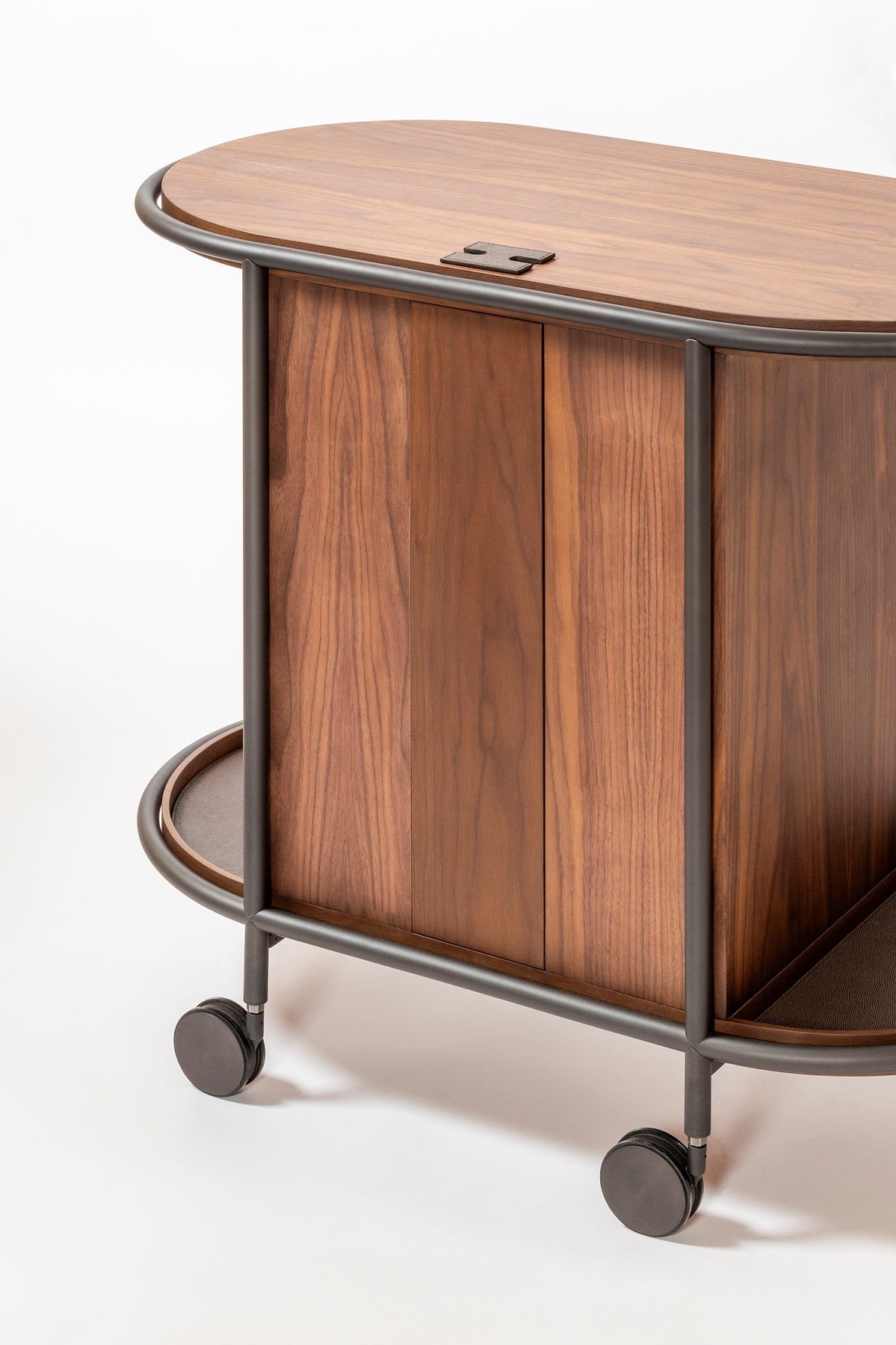 Giobagnara Arcade wood coffee and tea cart oval | Refined coffee and tea cart with a four-wheel structure in natural, walnut, or wenge wood | Metal frame and wheels available in chrome, bronze, or brass finishes | Features five organized drawers with sleek metal handles for storing coffee capsules, tea bags, and accessories | Includes porcelain coffee and tea cups with matching plates and silver graphic trim, plus wood trays and coasters | Designed for easy mobility and sophisticated presentation | Perfect 