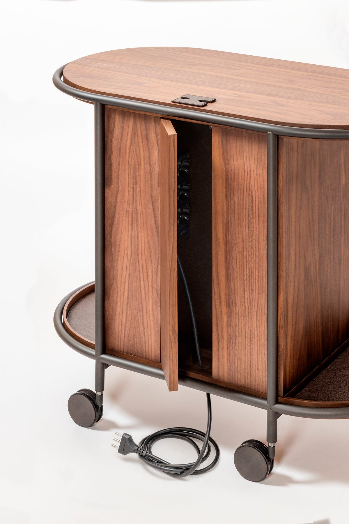 Giobagnara Arcade wood coffee and tea cart oval | Refined coffee and tea cart with a four-wheel structure in natural, walnut, or wenge wood | Metal frame and wheels available in chrome, bronze, or brass finishes | Features five organized drawers with sleek metal handles for storing coffee capsules, tea bags, and accessories | Includes porcelain coffee and tea cups with matching plates and silver graphic trim, plus wood trays and coasters | Designed for easy mobility and sophisticated presentation | Perfect 