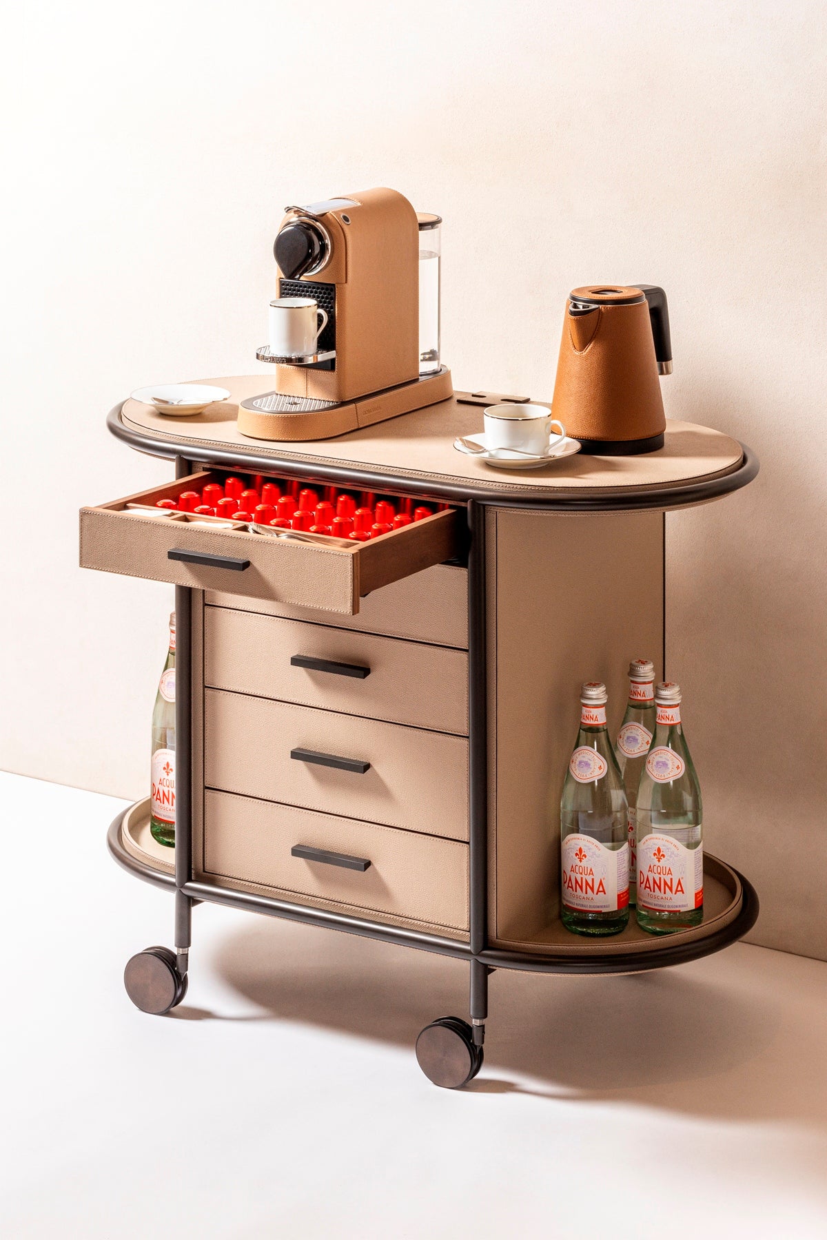 Giobagnara Arcade Coffee and Tea Cart Oval | Leather-covered four-wheel wooden structure with a metal frame and wheels available in three finishes | Features five drawers with sleek metal handles for organized storage of coffee capsules and tea bags | Includes a luxurious set of porcelain coffee and tea cups with matching plates, leather service trays, and coasters | Designed for mobility, combining functionality and sophistication | Furniture and Serveware | 2Jour Concierge, your luxury lifestyle shop