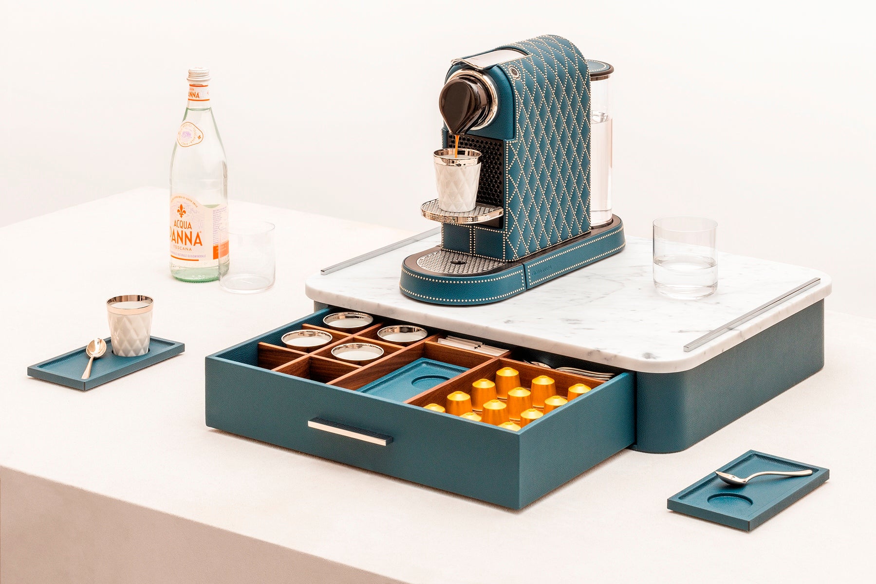Giobagnara Saint-Germain deluxe coffee and tea drawer organizer + cups | Luxurious organizer for Nespresso classic capsules and tea service | Leather-covered wood structure with metal inserts in three finishes | Top customizable in leather, Corian®, or marble (classic travertine or arabescato white) | Inner walnut wood partitions hold coffee spoons, sugar, 24 capsules, 6 double-wall borosilicate glass cups, and 6 nesting rectangular saucers (all included) | Option to replace glass cups with sieger porcelain